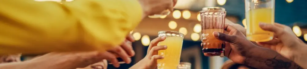 A group of people, holding up their glasses for a toast (only their arms and hands are visible - not their entire bodies).