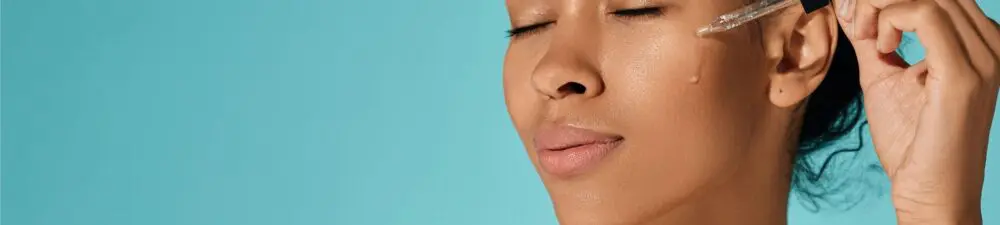 A woman applies facial skincare ointment to their face.