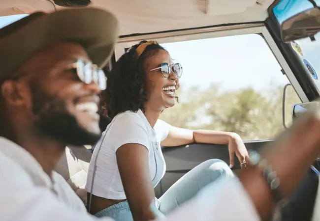 Couple in a car smiling, on a road trip