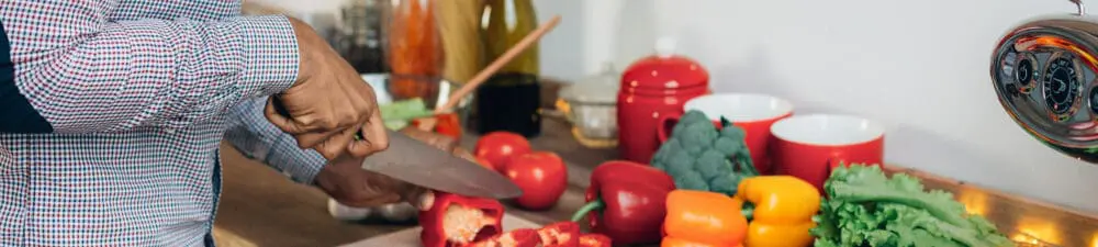 man in kitchen chopping vegetables