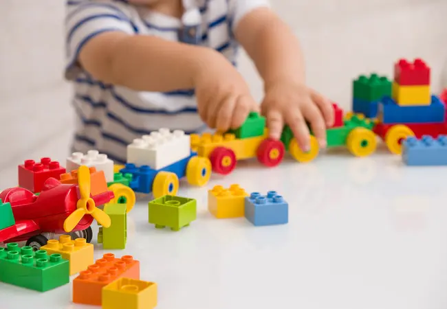 Child playing and building a train with legos.