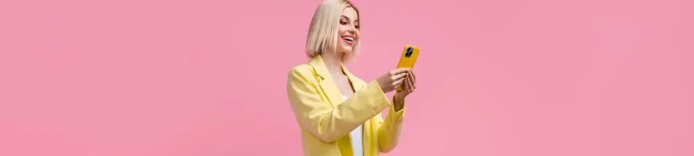 A fashionable influencer wears a yellow jacket and is on her phone.