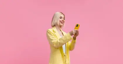 A fashionable influencer wears a yellow jacket and is on her phone.