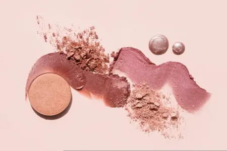 Cosmetics swatches. Peach, beige, red and coral toned styled cosmetics flat lay.