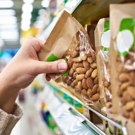 Consumer reaches out to grab a packaged bag of nuts