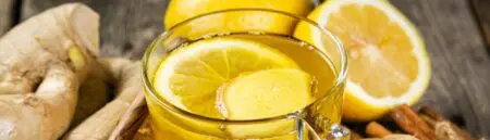 Image shows a lemon and honey tea with ginger shavings in a clear glass.