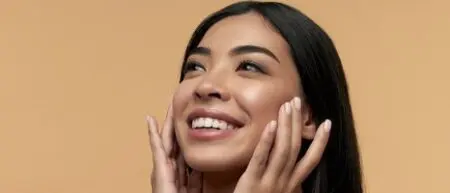 Diversity in Beauty: Brown woman with glowing skin rubs in a skincare cream.
