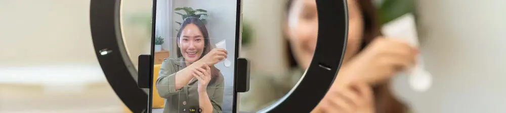 A lady filming content of trying on a hand cream with a ring light.