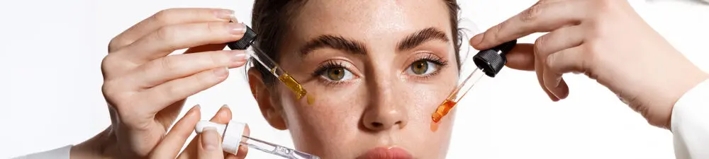 A lady showcasing beauty/skin serums on her face