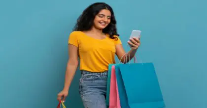 Gen Shopper, carrying several shopping bags and scrolling on their phone.