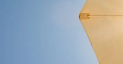 Bright sun shines through a beige umbrella