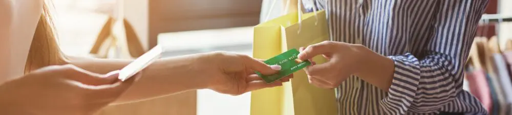 an individual is using their credit card to pay for their shopping in a retail store
