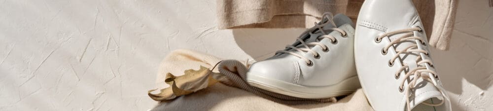 White sustainable trainers with cream background