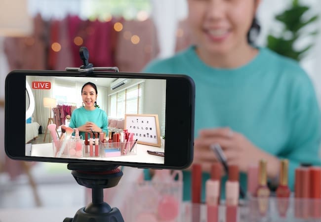 Gen Z Beauty Trends: Woman influencer records live beauty product review using their mobile.