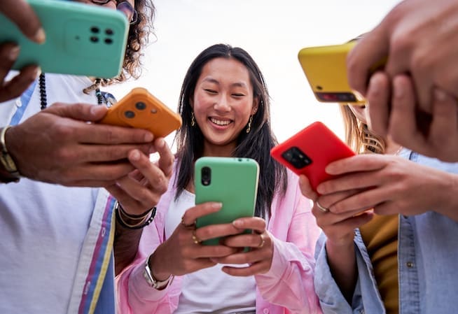 Gen Z Consumer Trends: Group of Generation Z's gathering in circle using their mobile phones.