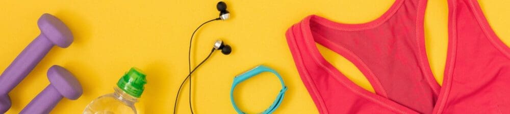 Brightly colored fitness equipment, including dumbells, headphones, water bottle and tank top on a bright yellow background.