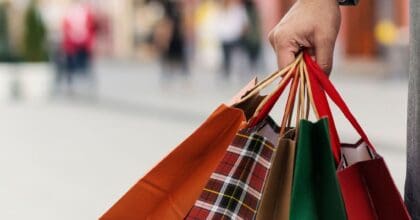 Woman's hand holding four Christmas shopping bags in street