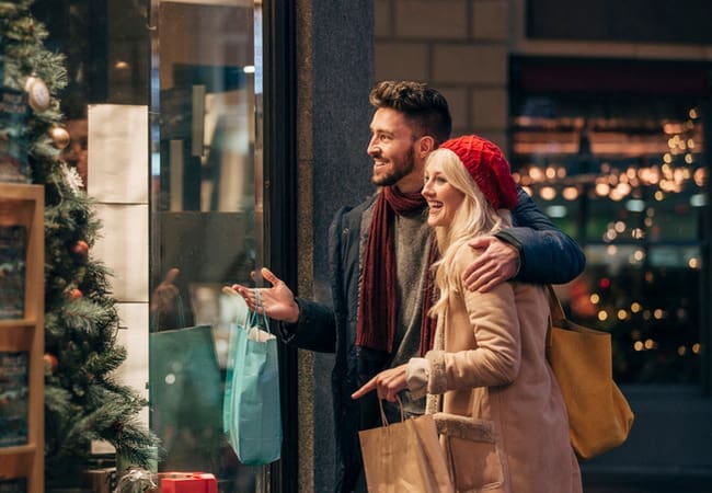 A couple Christmas window shopping holding shopping bags