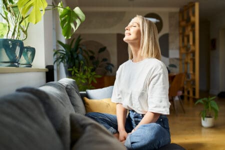 Woman sitting in living room enjoying the sunshine from the window