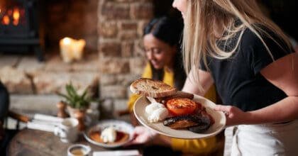 Waitress brings plates of breakfast to a couple in a cafe.