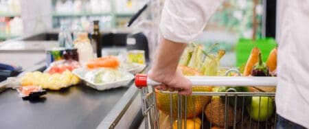 Man queuing to pay in a supermarket with a cart full of groceries