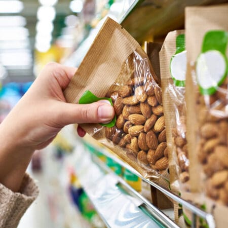 Consumer reaches out to grab a packaged bag of nuts