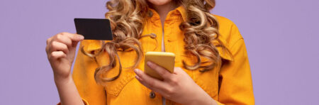 Woman holding a phone in one hand and a credit card in the other.