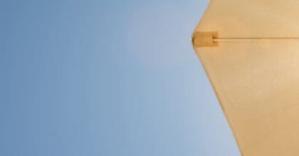 Bright sun shines through a beige umbrella