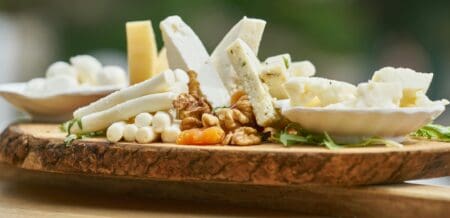 Wooden cheese board with a selection of different cheeses.